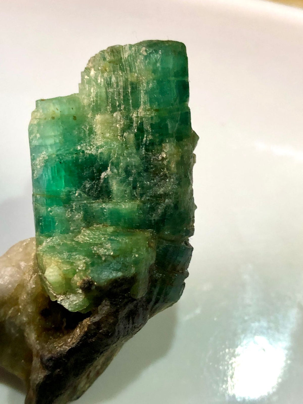 Raw emerald crystal on a white background