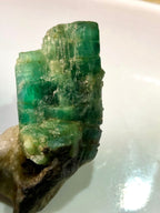 Raw emerald crystal on a white background