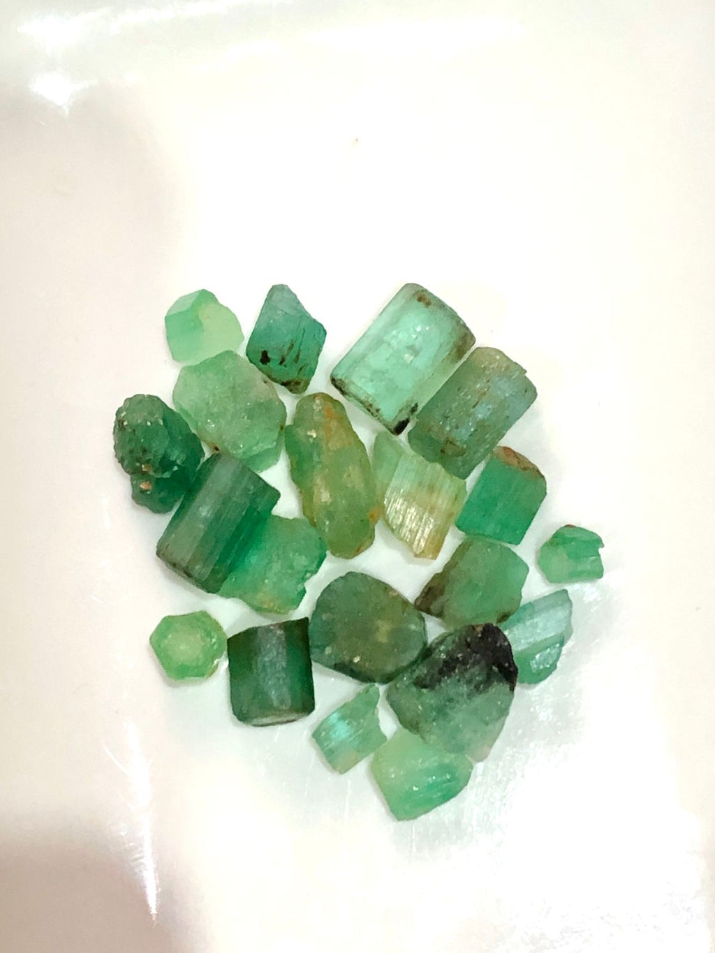 Collection of green raw emeralds on a white background